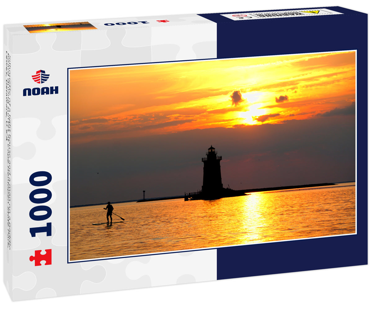 Silhouette of a light house and a man on a paddle board during sunset at Cape Henlopen State Park, Lewes, Delaware, U.S.A
