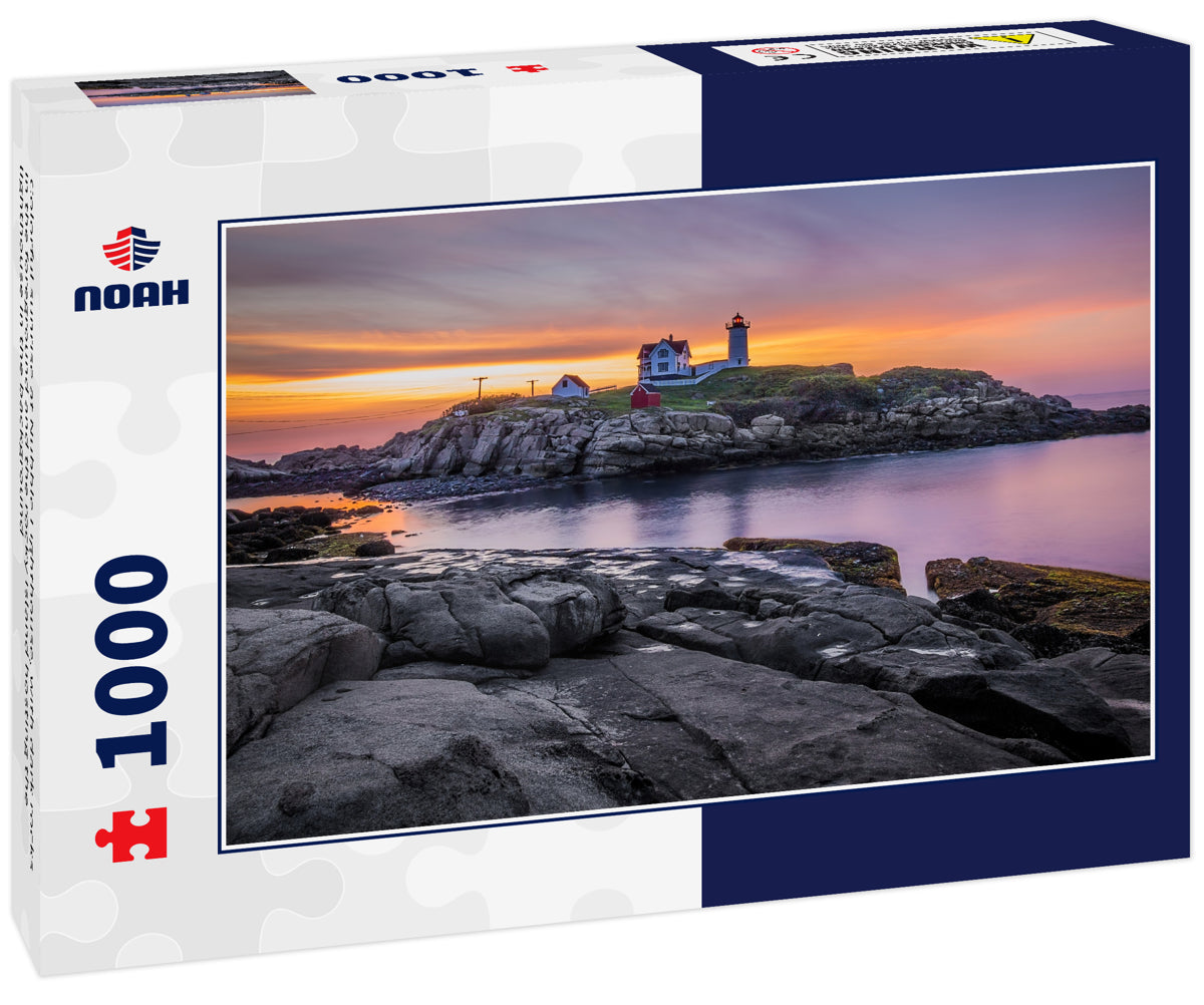 Colorful sunrise at Nubble Lighthouse, with dark rocks in the foreground and the rocky island hosting the lighthouse in the background