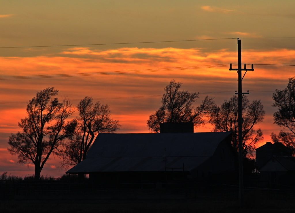 Sunset in the country with a house, tree's and power lines south of Lyons Kansas USA out in the country