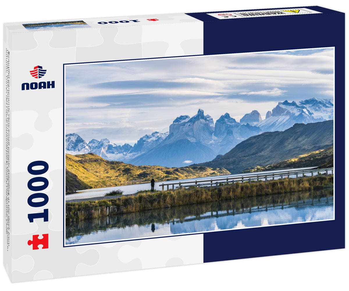 Beautiful panoramic view small people standing at the dock from the lake with Cuernos, horn mountains peak with lenticular cloud in autumn, Torres del Paine national park, south Patagonia, Chile