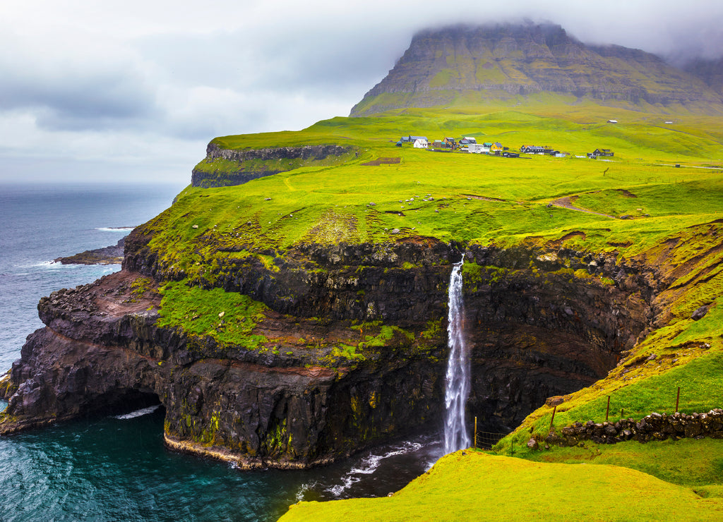 Dramatic waterfall on Faroe Islands and the village Gasadalur