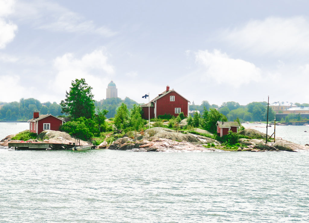 A small island with a house with the Helsinki skyline visible in the background. Taken near Suomenlinna, Finland