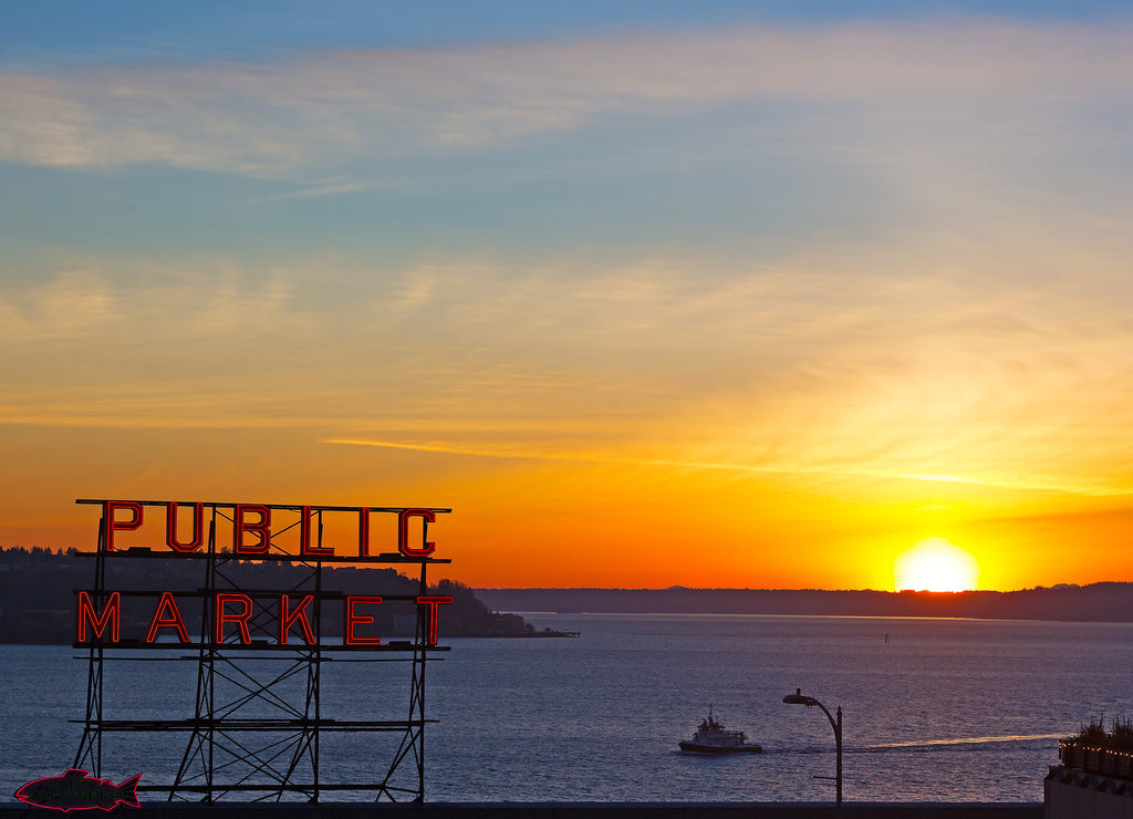 Spectacular sunset over Puget Sound photographed from the Pike Public Market in Seattle, Washington, USA. Winter sunset, water, mountains on horizon and Public Market neon sign