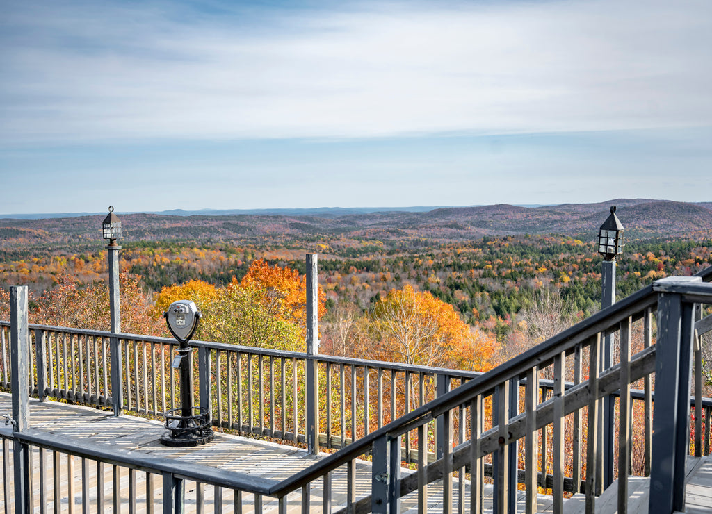 Observation deck with stationary coin binoculars overlooking the hills overgrown with autumn maples in Vermont