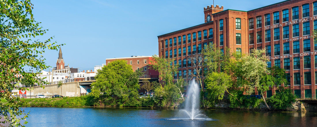 Noah Jigsaw Puzzle Fountain on the Nashua River against the background of a historic cotton factory building with a clock tower in the old industrial park of Nashua. New Hampshire, USA panorama 2000 pieces