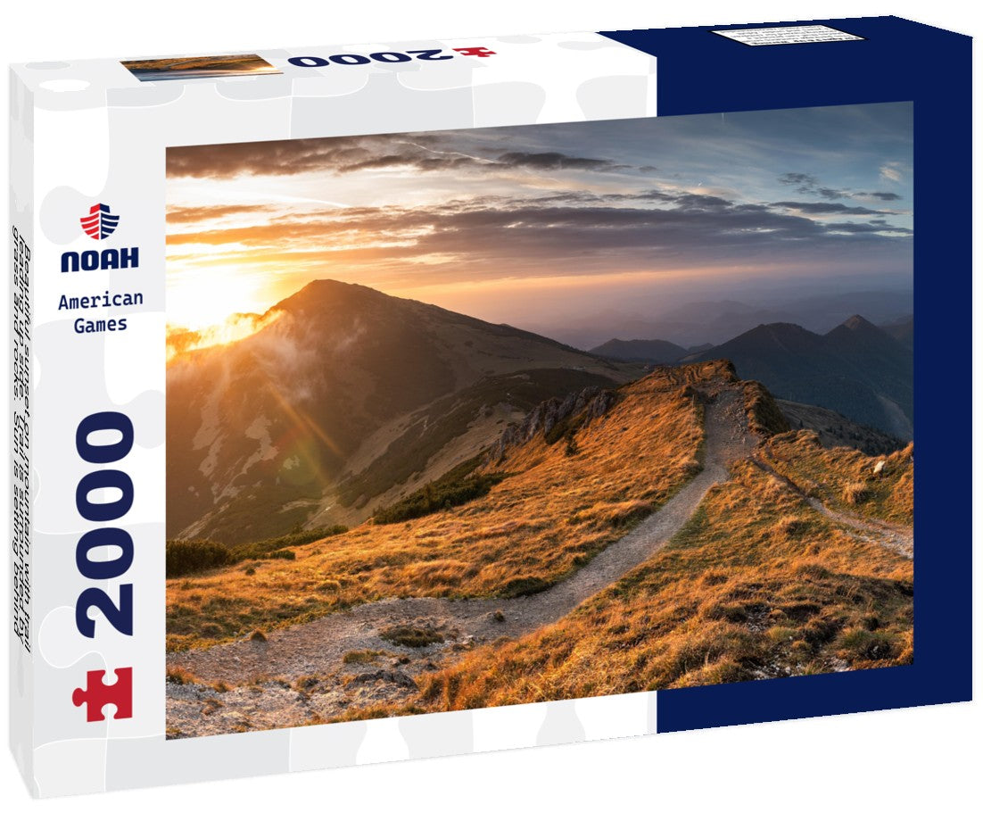 Noah Jigsaw Puzzle Beautiful sunset on mountain with trail leading up side. Trail is surrounded by grass and rocks. Sun is setting behind mountain, casting warm glow on 2000 pieces