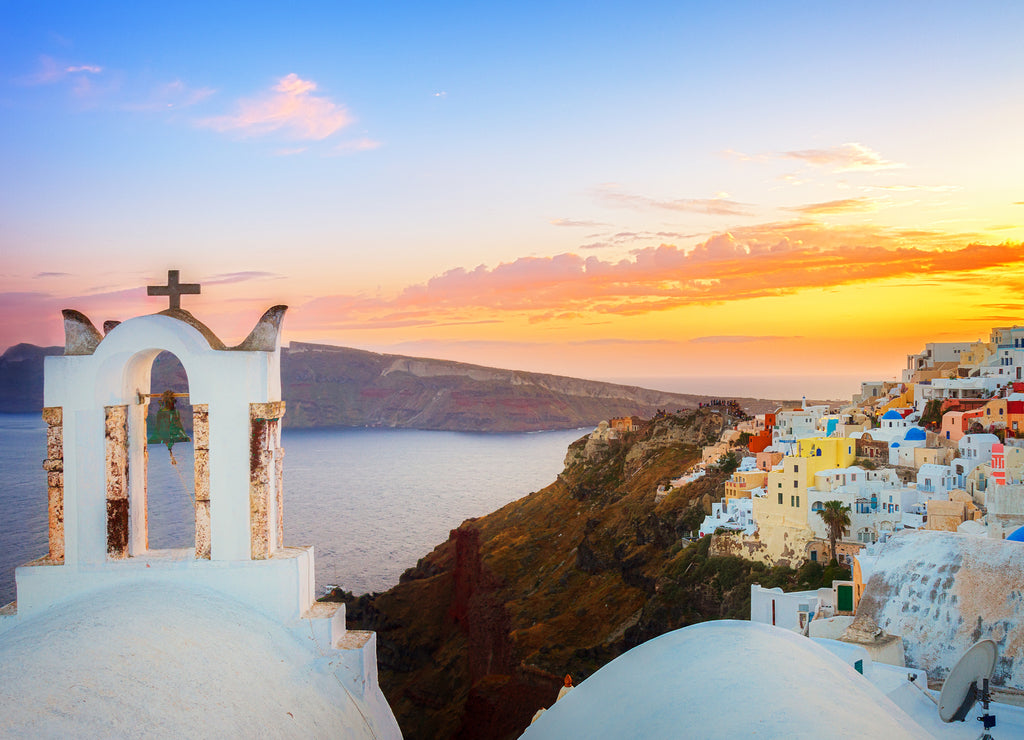 Cityscape of Oia, traditional greek village of Santorini, with white bellfry at sunset, Greece