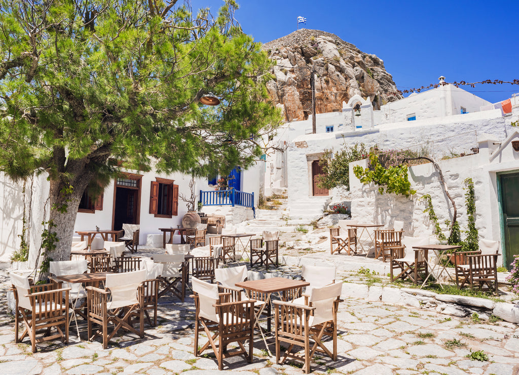 Traditional greek street with flowers and cafe tables in Amorgos island, Cyclades, Greece