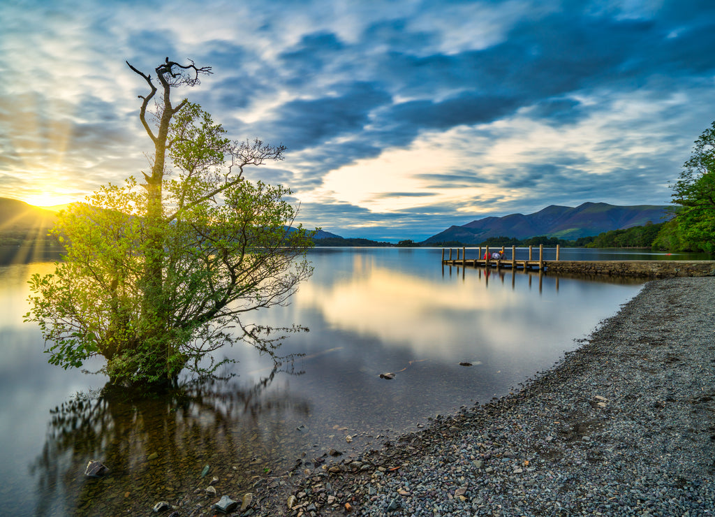 Sunset with dramatic clouds and wooden jetty at Derwentwater Lake in the Lake District, UK