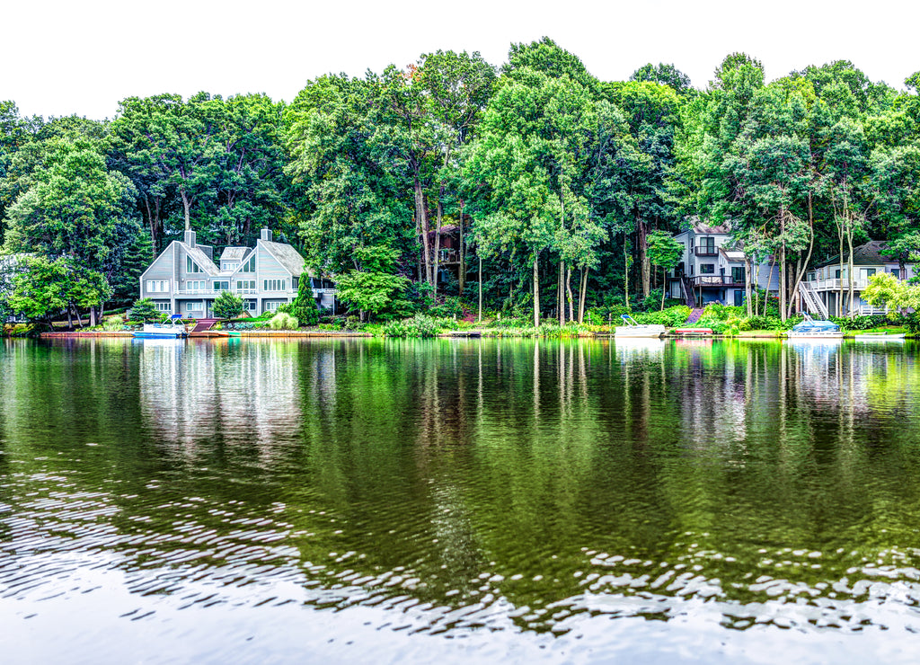 Lake Audubon with lakefront waterfront houses in Reston, Virginia with reflection of summer green foliage on trees