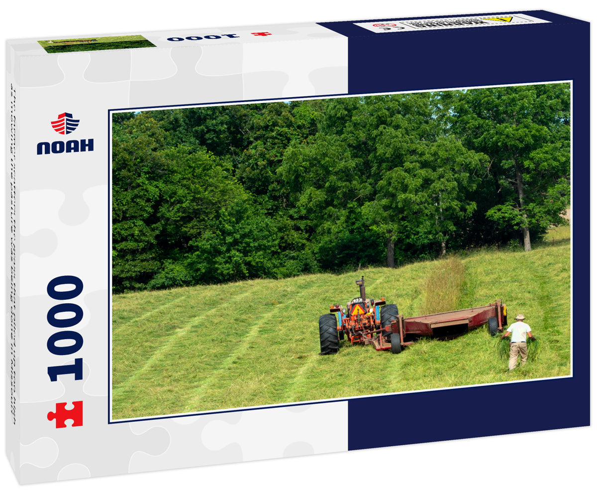 The farmer scatters the grass that piled up too high as mowing the pasture was being done in Missouri
