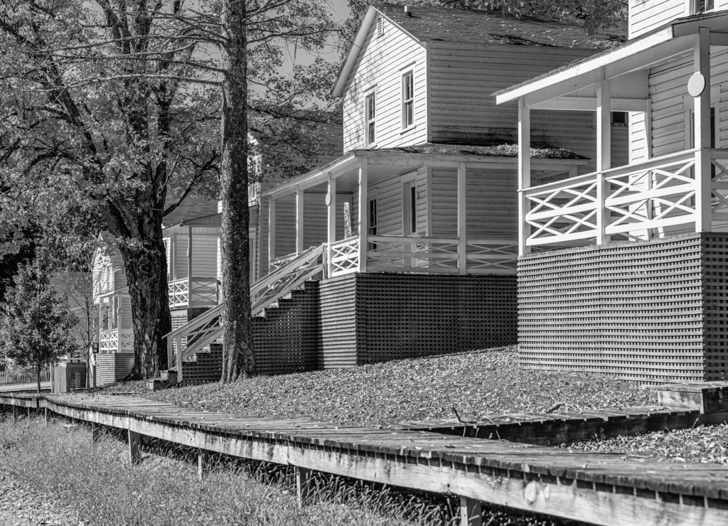 Row of old residential white houses single family buildings in Cass, West Virginia with street road view in black white