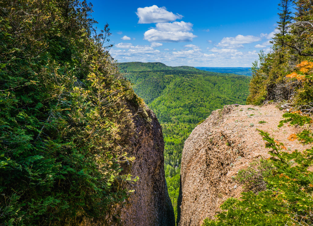Crack in the rocks in the Percé Unesco Geopark, not far from the famous Percé rock, with in the background view on the forest of Gaspésie, Quebec