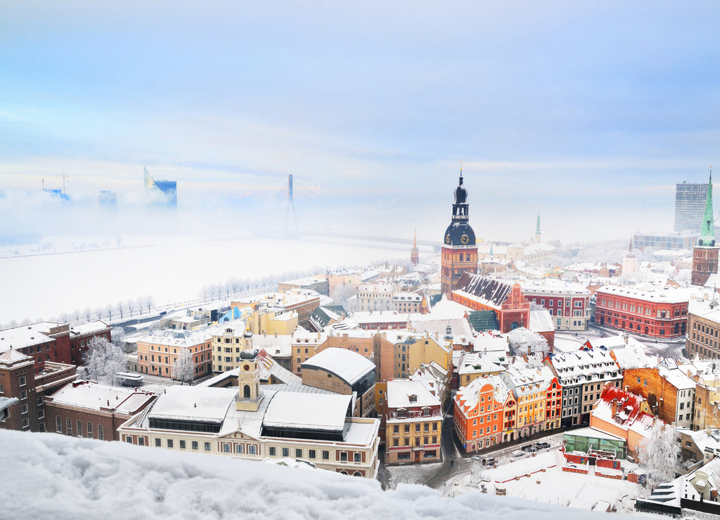Panoramic view of the Riga old town and Daugava river from St. Peter's Church on a clear winter day. Morning fog and snow-covered houses. Latvia
