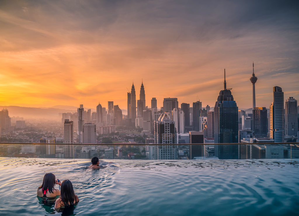 Traveler looking view skyline Kuala Lumpur city in swimming pool on the roof top of hotel at sunrise in Kuala Lumpur, Malaysia