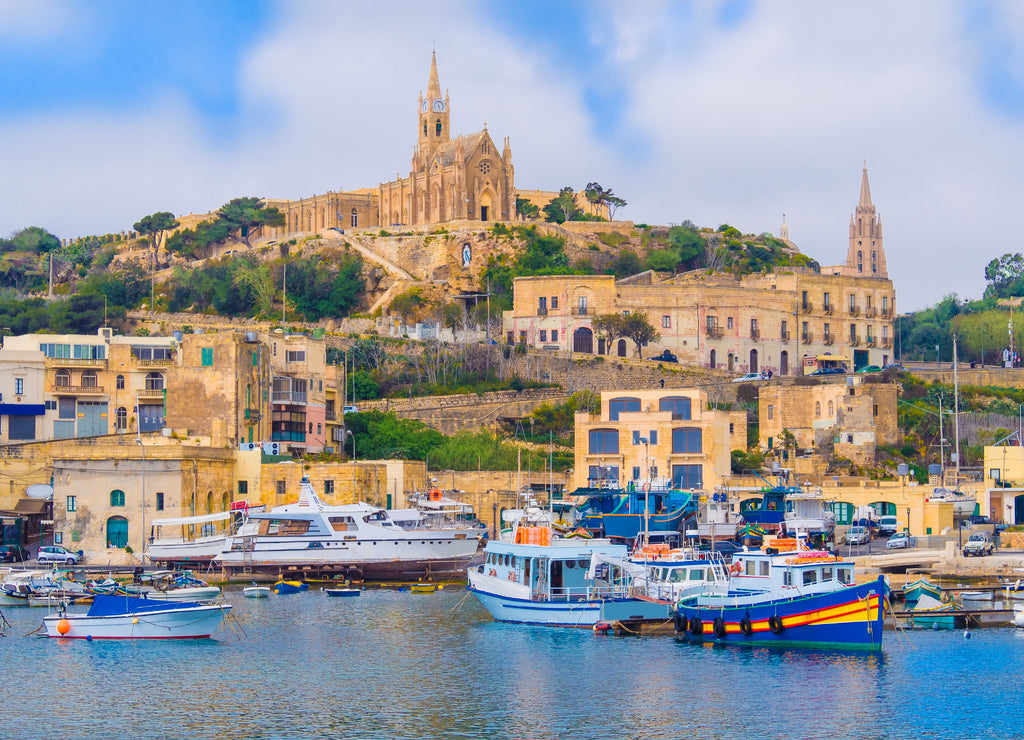 Cityscape view of Gozo island with medieval architecture and passenger boats on the harbour in Malta
