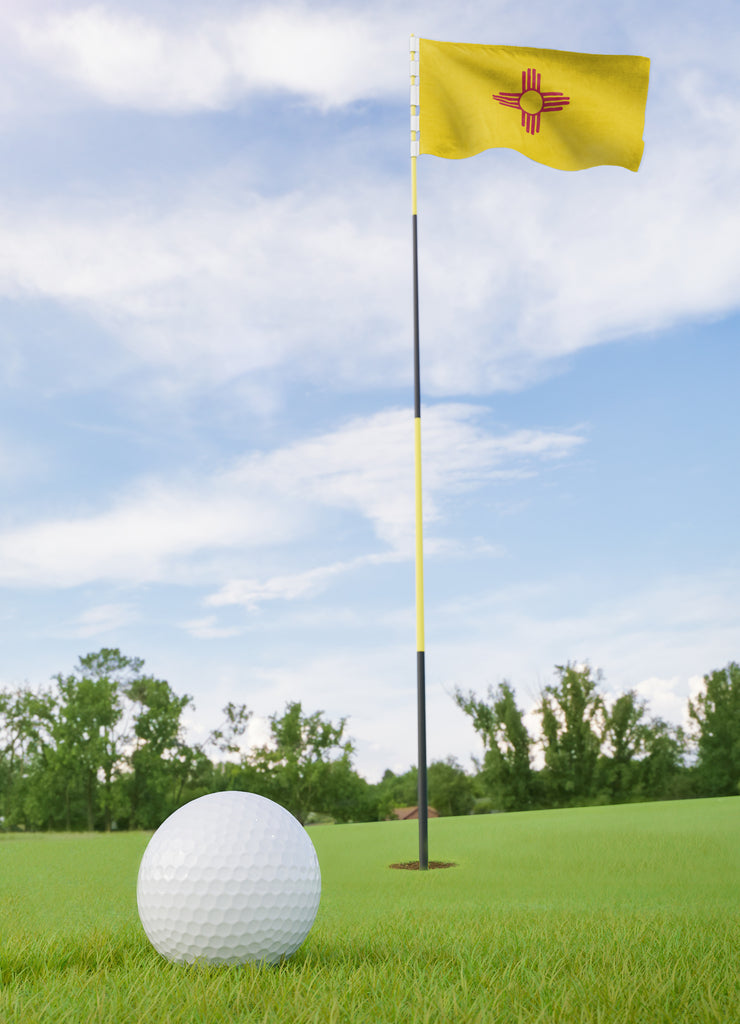 New Mexico flag on golf course putting green with a ball near the hole