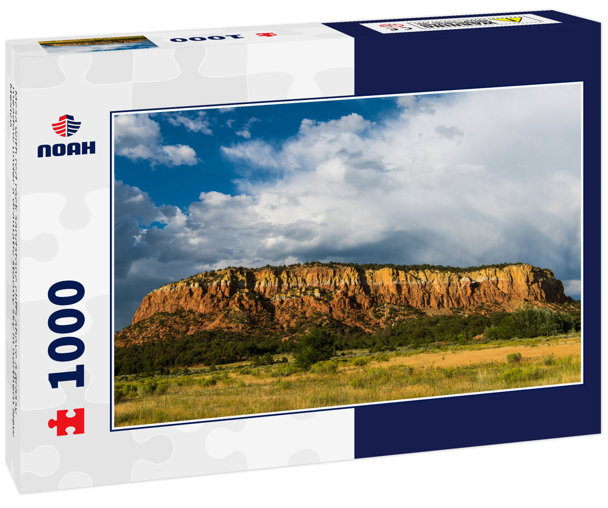 Mesa with red rock sandstone cliffs above a grassy meadow under a dramatic stormy sky in northern New Mexico