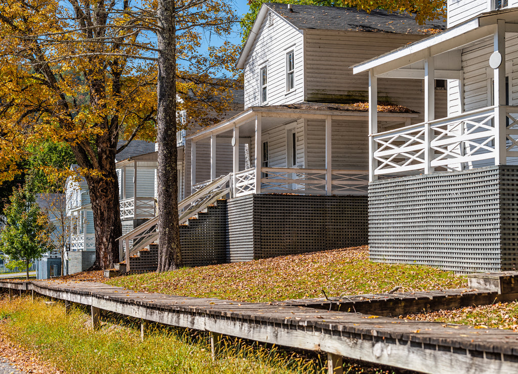 Row of old residential white houses single family buildings in Cass, West Virginia with street road view