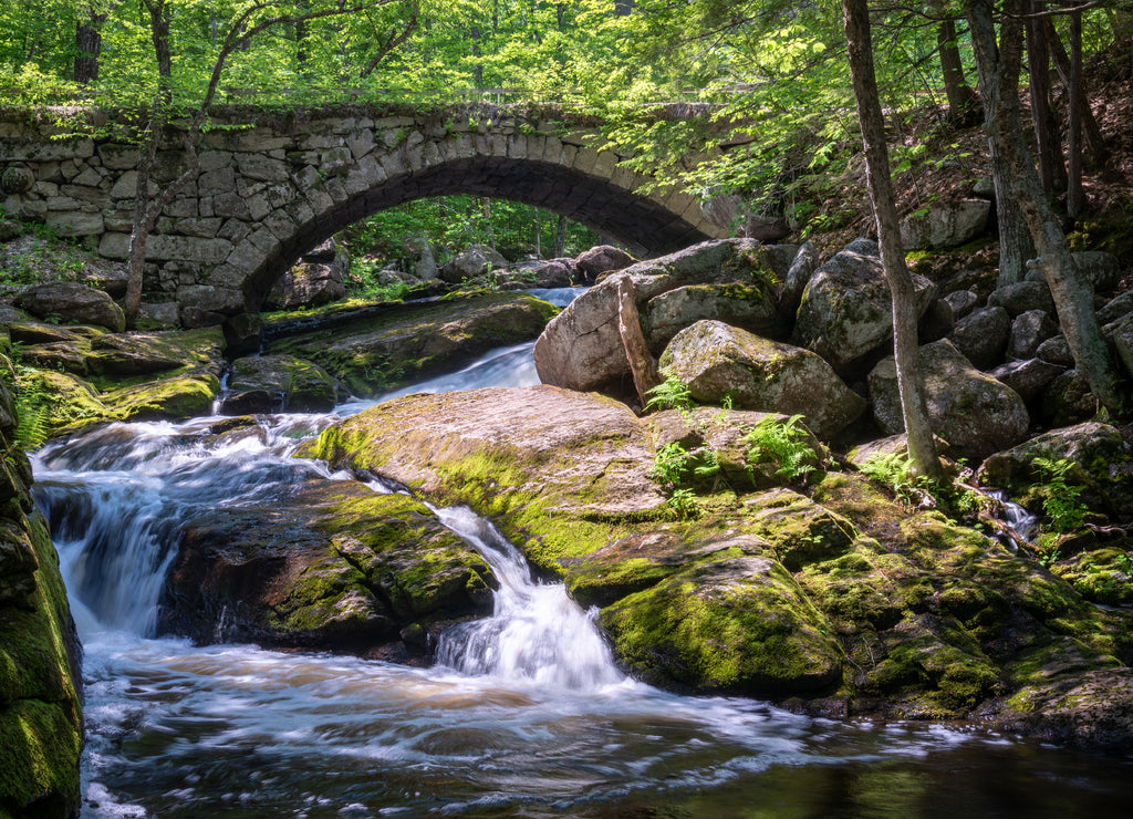 Stone arched bridge over waterfalls with fall foliage in Hillsborough, New Hampshire, New England
