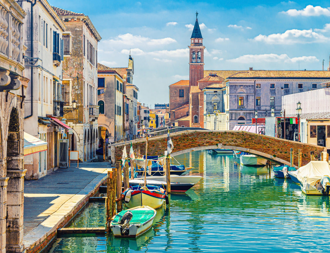 Noah Jigsaw Puzzle Chioggia cityscape with narrow water canal with colorful boats, old buildings, brick bridge and tower of the church San Giacomo Apostolo, blue sky in summer, Veneto region, northern Italy 1000 pieces