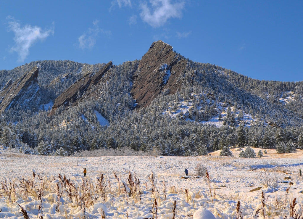 Winter view of the Flat Iron Mountains peak in fresh snow, with blue sky, pine trees and hiking trails in Boulder, Colorado