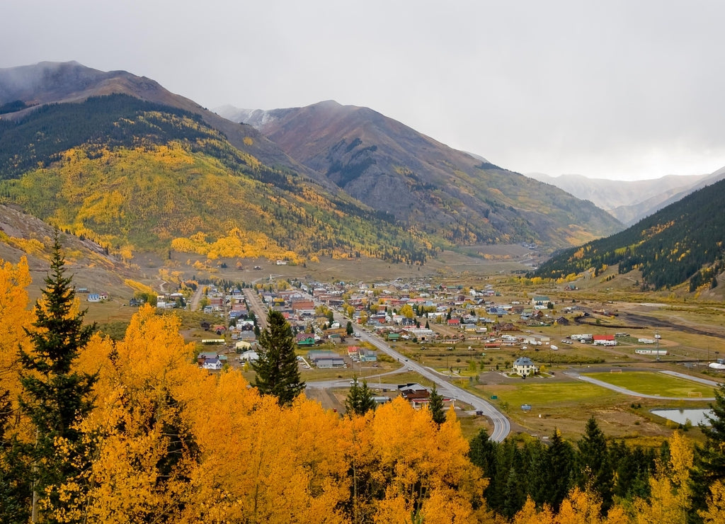 Silverton Colorado surrounded by gold and orange autumn leafed aspen trees on a foggy fall day in San Juan County, Colorado