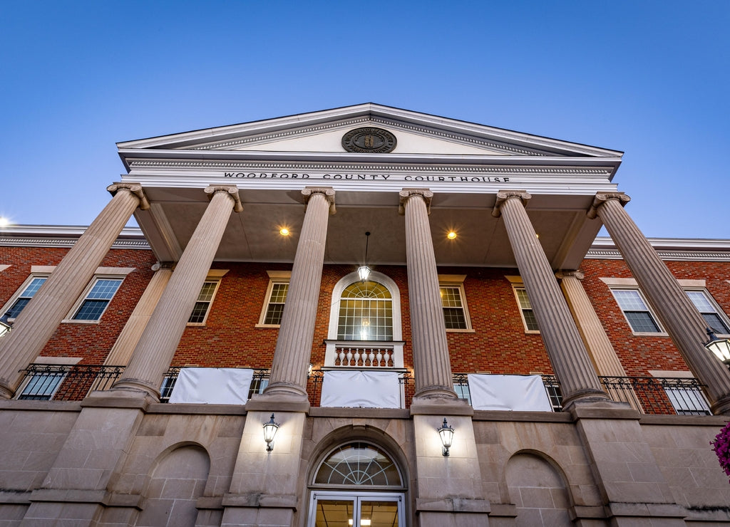 Woodford county courthouse in Versailles, Kentucky as seen from the sidewalk in front of it during early morning hours with lights still shining