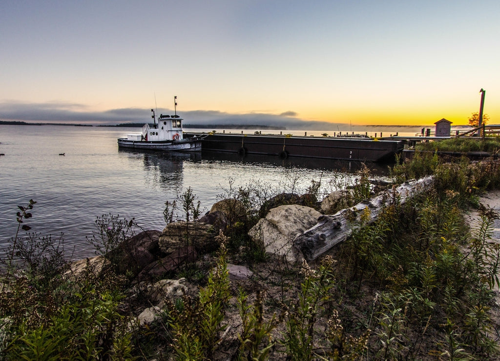Lake Superior Sunrise. Small tugboat moored on a Lake Superior dock with a coastal sunrise in the background. Grand Island National Recreation Area. Munising, Michigan