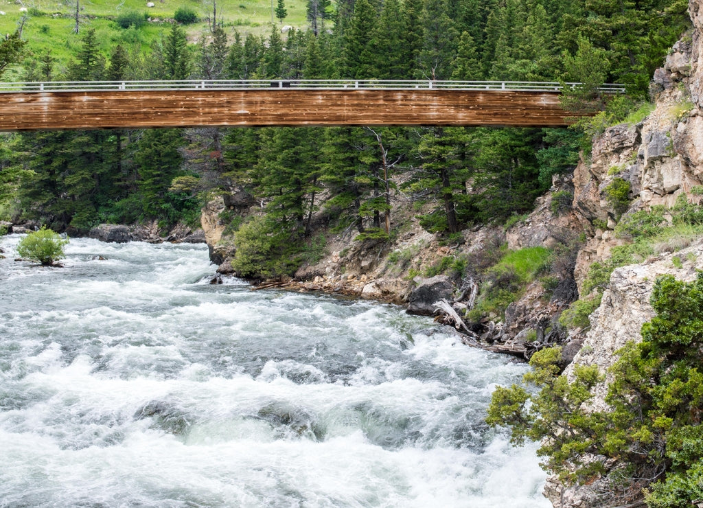weathered wooden bridge overlooking the scenic Boulder River with it's rocky hillsides and lush forest near Big Timber, Montana