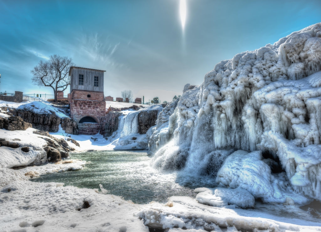 Sioux Falls Park waterfall with ice and snow. Cascading snowmelt water pouring over the top into a pool of standing water
