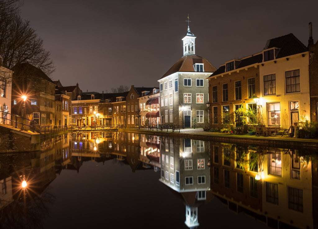 Scenic view of buildings along a canal in the historic city of Schiedam, Netherlands. Tall building with spire is known as 'The Porters' Guild House'.