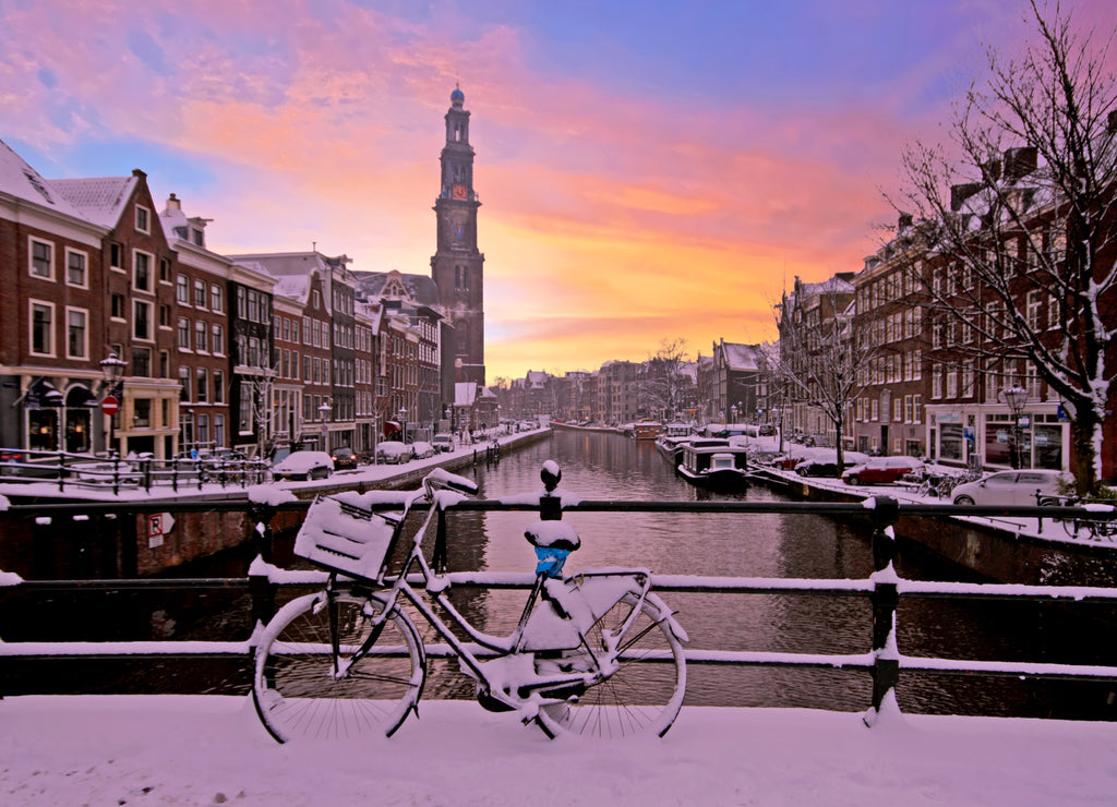 City scenic from snowy Amsterdam with the Westerkerk in the Netherlands at sunset