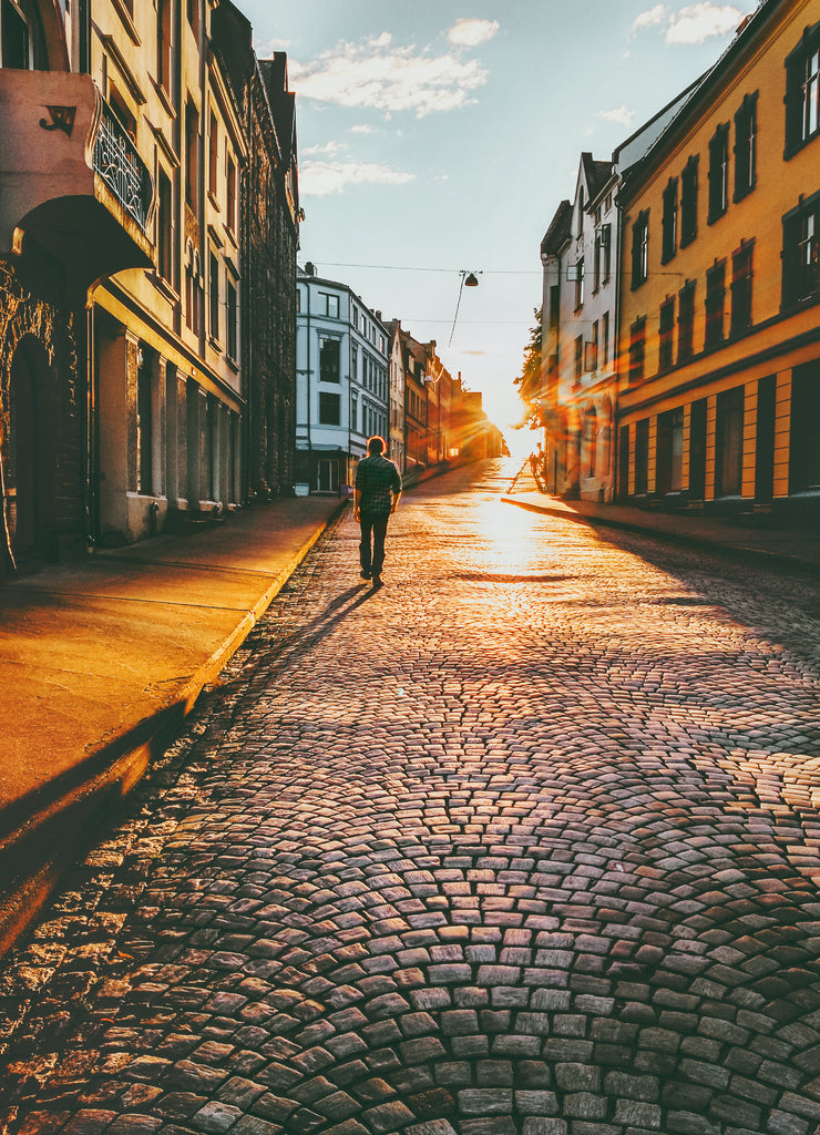 Man tourist walking in sunset street Travel Lifestyle concept vacations cobblestone road Alesund city in Norway