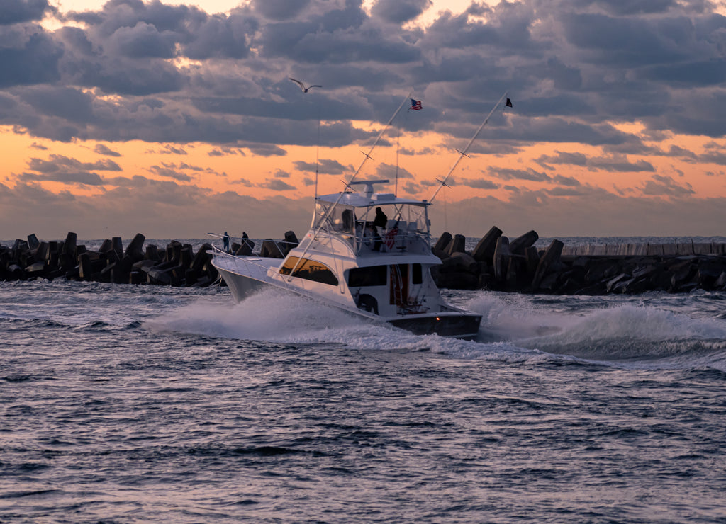 Motor boats heading out of Manasquan inlet at sunrise to go fishing, New Jersey