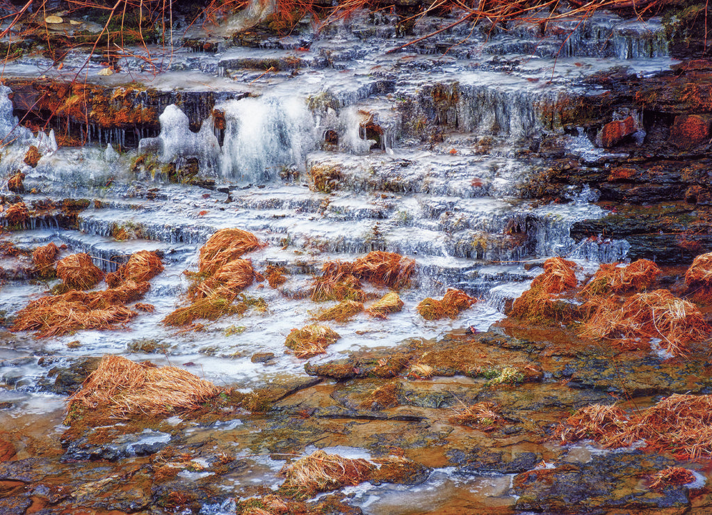 waterfall in spring forest. Small ice waterfalls on the edge of a creek in Binghamton in Broome County in Upstate New York. Snow has melted but the frozen water still remains on the rock ledges