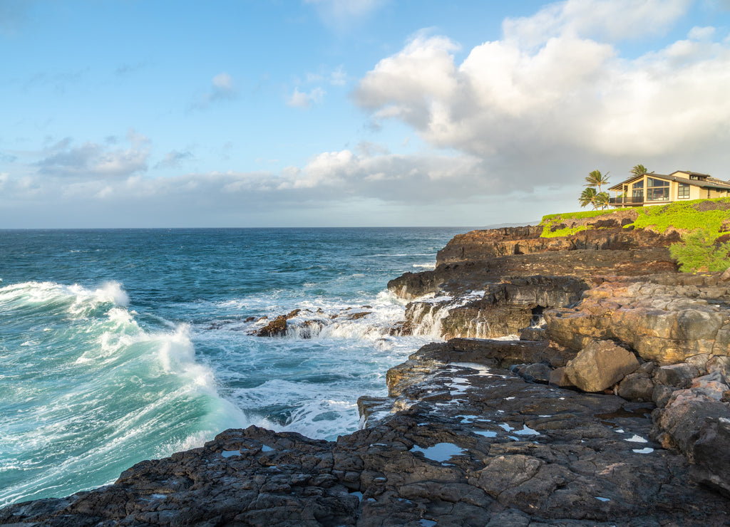 Ocean surf hitting the basalt cliff as water from previous wave back flashing to the sea, Kauai, Hawaii