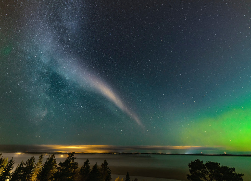 Weak Northern Lights on horizon and atmospheric phenomenon 'STEVE' crossing Milky Way. Steve appears as a purple and green light ribbon in the sky at an altitude of 450 km. Northern Sweden Scandinavia