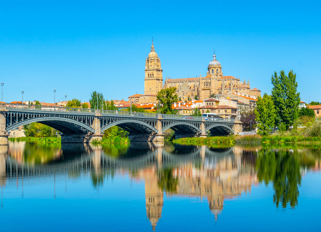 Cathedral at Salamanca reflected viewed behind bridge of enrique esteven on river Tormes, Spain