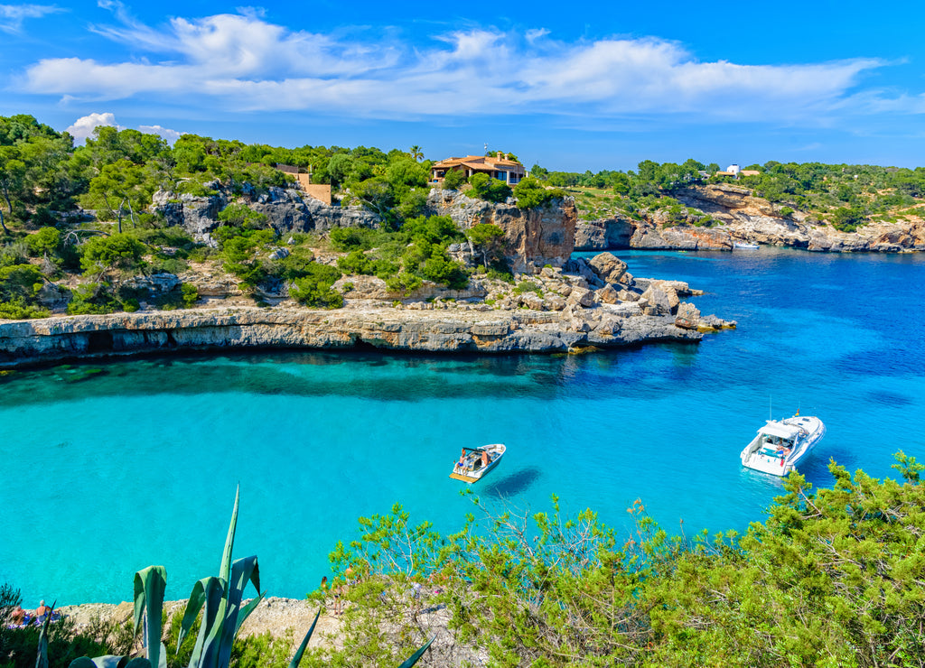 Summer holiday scene with boats on turquoise sea water of Mallorca in Cala Llombards beach, Palma de Mallorca in Spain