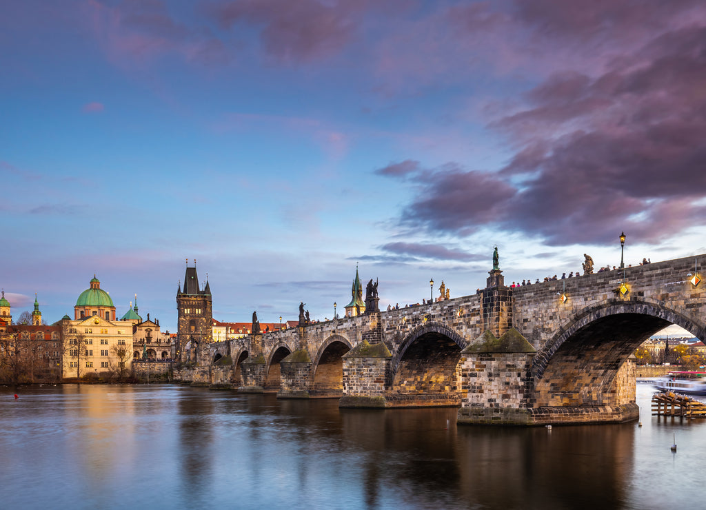 Prague, Czech Republic - Beautiful purple sunset and sky at the world famous Charles Bridge (Karluv most) and St. Francis Of Assisi Church on a winter afternoon