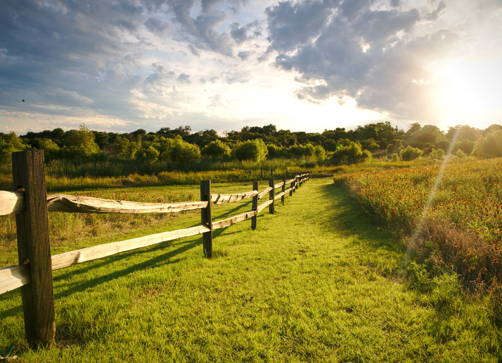 The sun sets over a ranch fence in North Texas