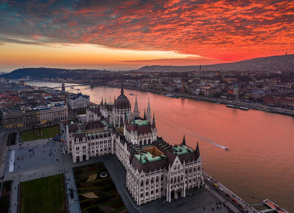 Budapest, Hungary - Aerial panoramic drone view of the Hungarian Parliament building on a winter afternoon with an amazing dramatic colorful gold and red sunset sky