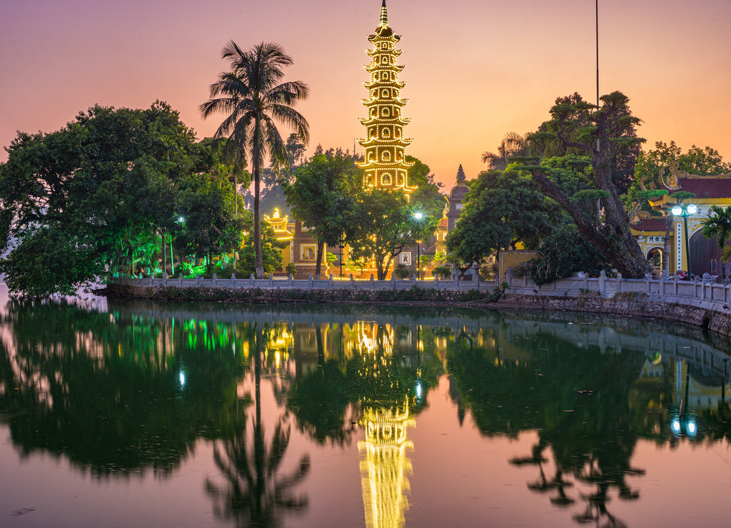 Hanoi buddhist pagoda on West Lake, colorful sunset, illuminated temple, water reflection. Chua Tran Quoc on Ho Tay at Hanoi