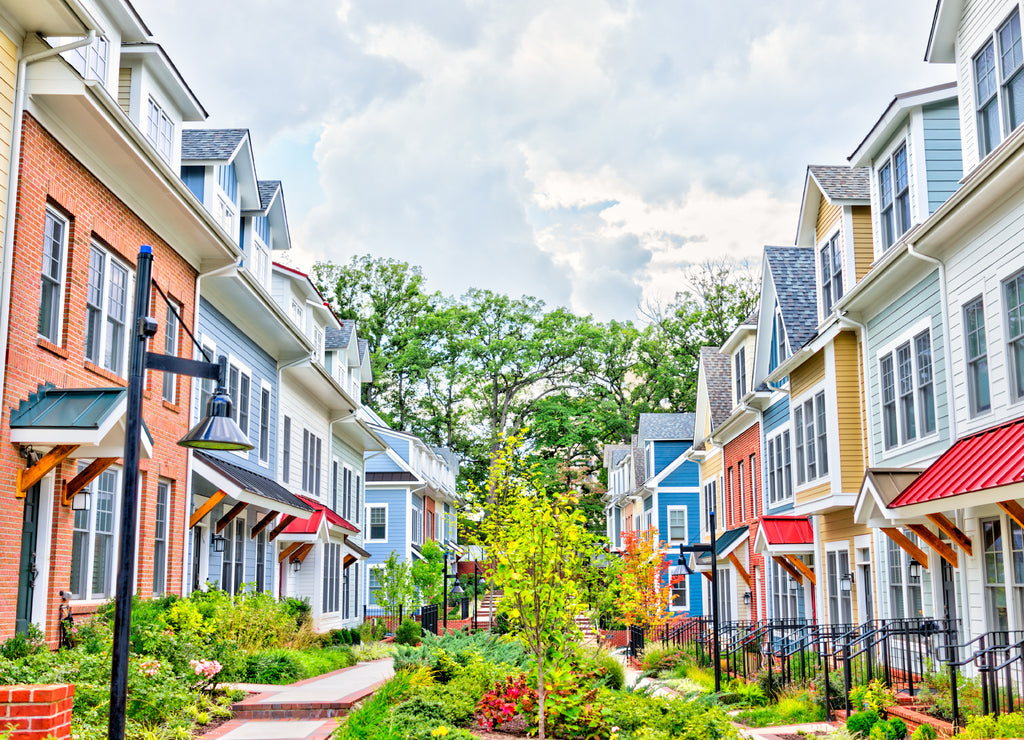 Row of colorful, red, yellow, blue, white, green painted residential townhouses, homes, houses with brick patio gardens in summer, Washington D.C.