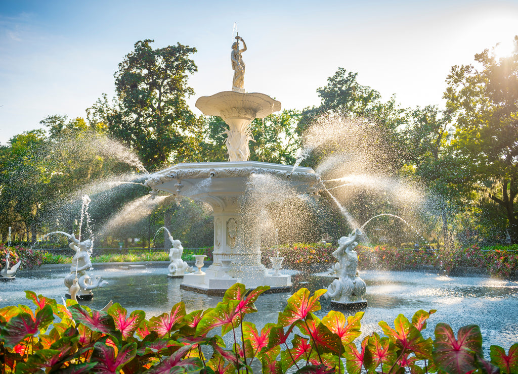 Scenic summer view golden sunlight shining through water spray of the old fountain (built in 1858) in Forsyth Park, Savannah, Georgia, USA