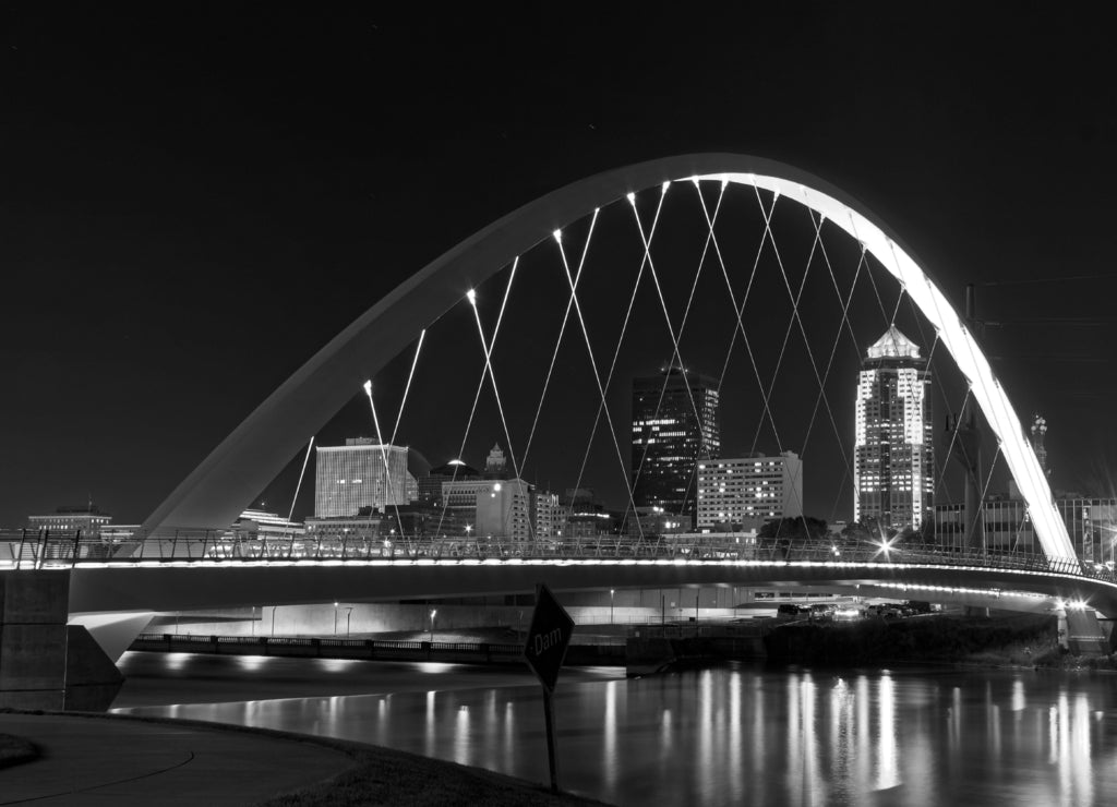Women of Achievement Bridge that spans the Des Moines River - one of the central features of Des Moines, the skyline of Des Moines is clearly visible through the lit arch, Iowa USA in black white