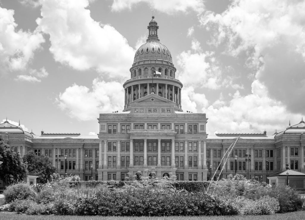 Texas State Capitol in Austin, Texas on a sunny summer day with colorful flowers in the front yard in black white