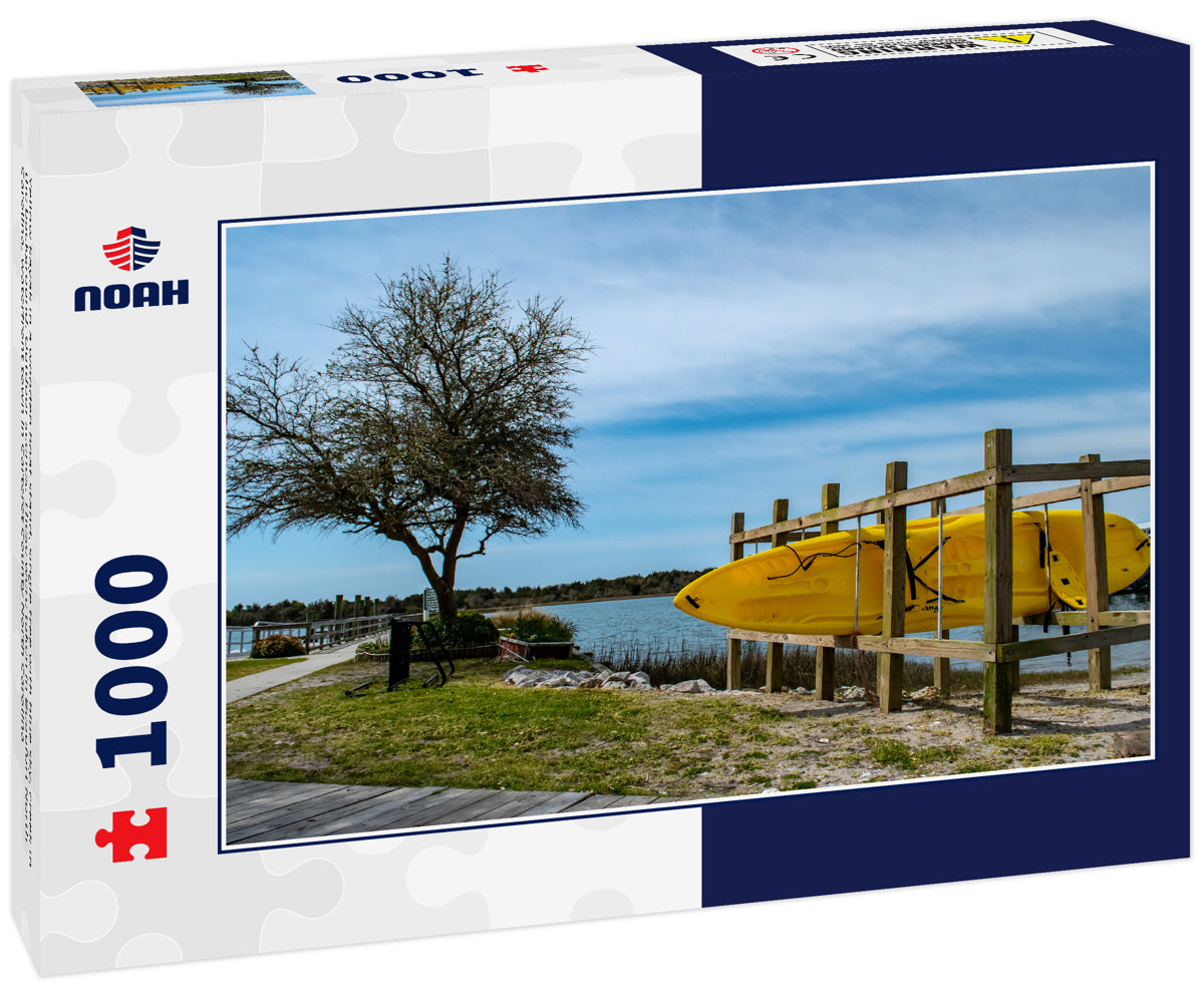 Yellow kayak in a wooden boat stand, single tree with blue sky, creek in the background. Outdoor scenes. These were taken in Beaufort North Carolina, waterfront town in Carteret County North Carolina