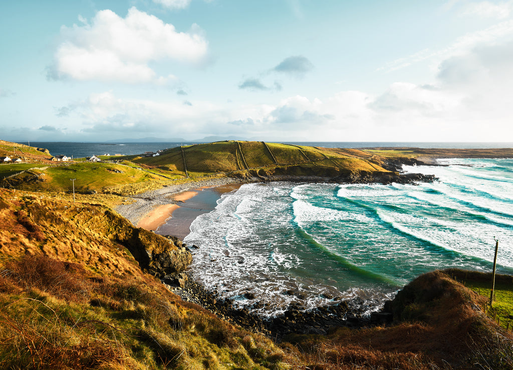 Beautiful Irish bay in Donegal with turquoise waters and large waves crashing on the beach of the small village of Muckross